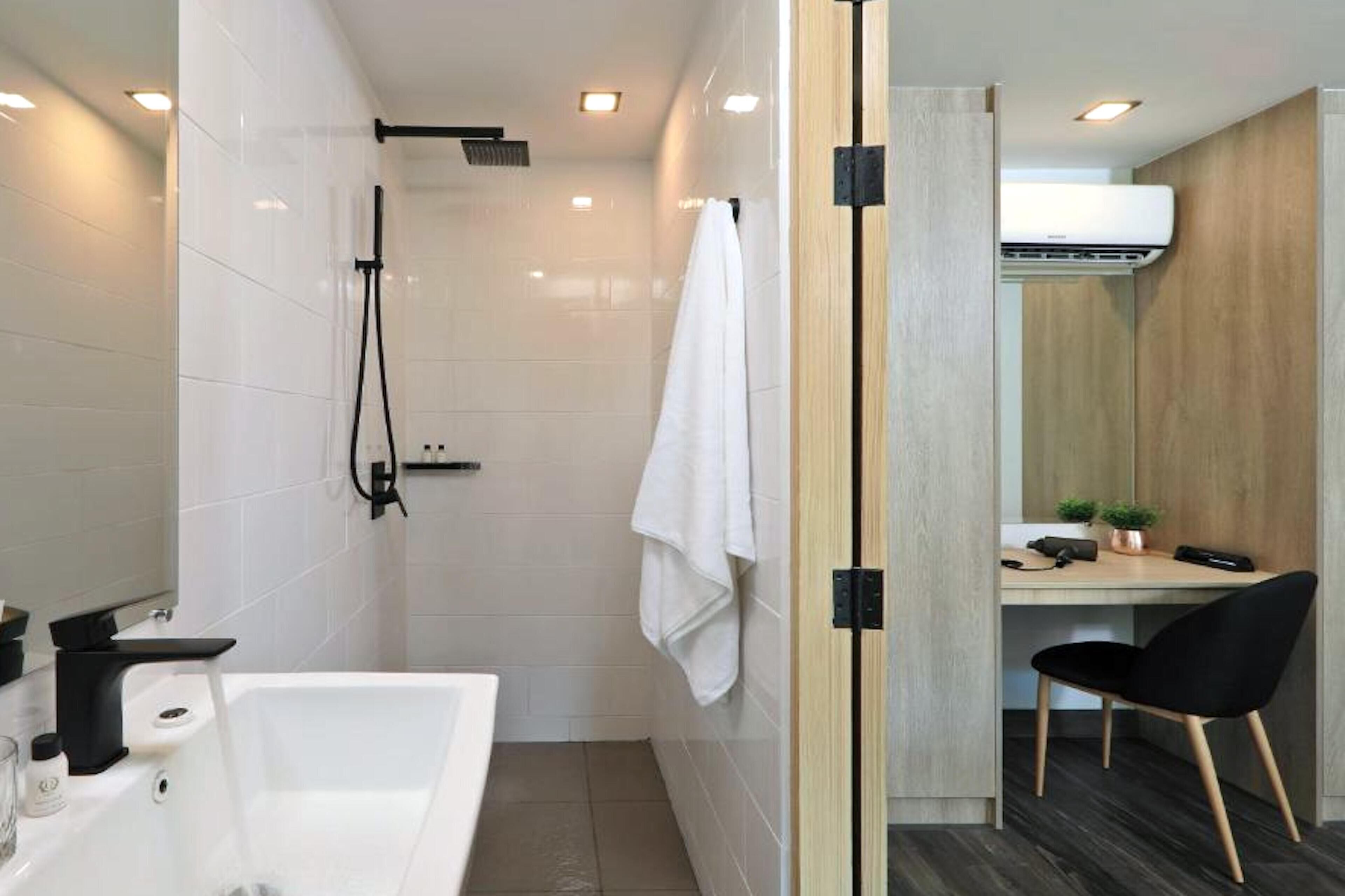 Un baño moderno con ducha, bañera y un escritorio con silla.
