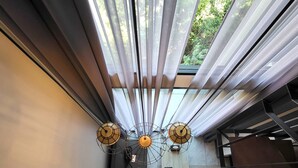 A modern interior with a sloped ceiling, large windows with sheer curtains, and three unique wall-mounted light fixtures.