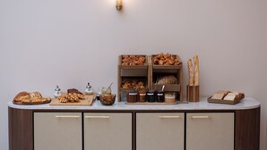 Una mesa de buffet con panes, pastas y frascos de conservas.