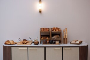 Una mesa de buffet con panes, pastas y frascos de conservas.