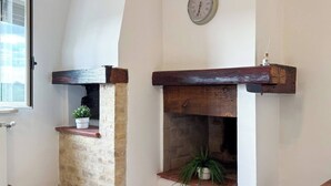 Una habitació amb una xemeneia, un rellotge a la paret i una finestra.