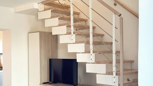 A modern interior with a wooden staircase, a flat-screen TV, and a minimalist design.