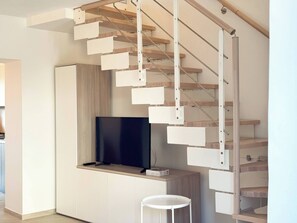 Een modern interieur met een houten trap, een flatscreen televisie en een minimalistisch design.