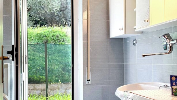 Uma casa de banho com sanita, lavatório, chuveiro e uma porta de vidro para um jardim.