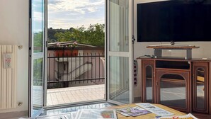 Quarto com porta de vidro deslizante que dá para uma varanda, televisão de tela plana e um armário de madeira.