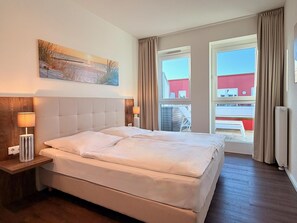 Et hotelværelse med en stor seng, to sengeborde med lamper, et billede på væggen og udsigt ud