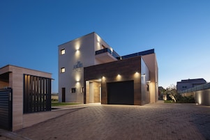 Un bâtiment moderne doté d’un toit plat, d’un garage et d’une allée pavée.