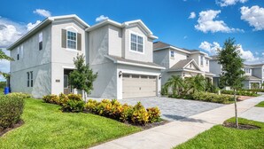 A modern two-story residential building with a garage, surrounded by well-maintained lawns and small trees.