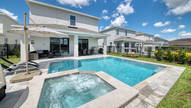 A residential area with a swimming pool, outdoor seating, and a covered patio.