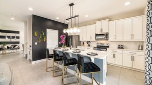 A modern kitchen with white cabinets, a central island with bar stools, and a black and white color scheme.