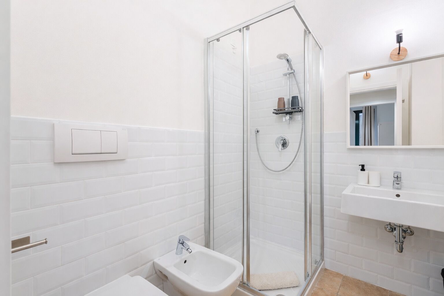 Un baño moderno con ducha envuelta en vidrio, lavamanos blanco y retrete.