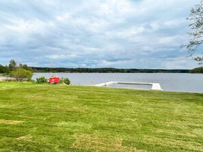 A grassy area with a dock extending into a lake, surrounded by trees and a cloudy sky. - 4 Star Holiday Home in Ammeberg (Åmmeberg)