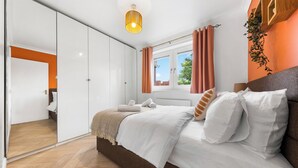 A modern bedroom with a large bed, a wardrobe, and a window with curtains.
