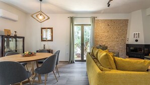 A modern living room with a dining area, a stone accent wall, and a fireplace.