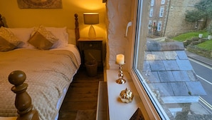 Un dormitorio con cama, lámpara de noche y vistas a la calle.
