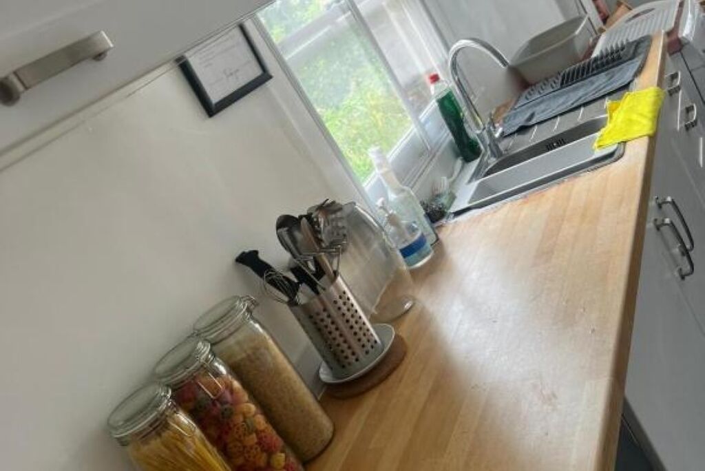 Una cocina con encimera de madera, un rallador y botes de especias.