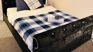 A bed with a checkered blanket, a pillow, and a rolled towel. - Cozy Accrington Retreat (Accrington)