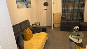 A living room with a sofa, a coffee table, and a door leading to another room. - Cozy Accrington Retreat (Accrington)