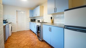 A kitchen with light blue cabinets, a white refrigerator, a stove, and a microwave. - Cozy Accrington Retreat (Accrington)