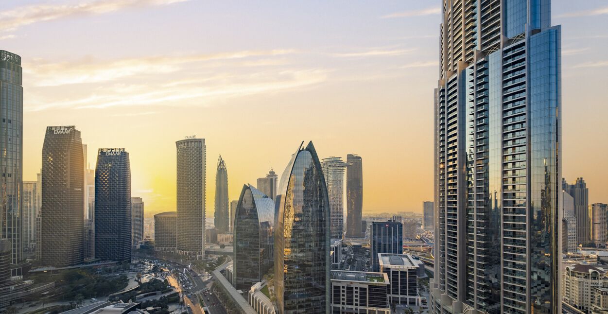 A cityscape with modern high-rise buildings, including a distinctive curved skyscraper and several rectangular structures.