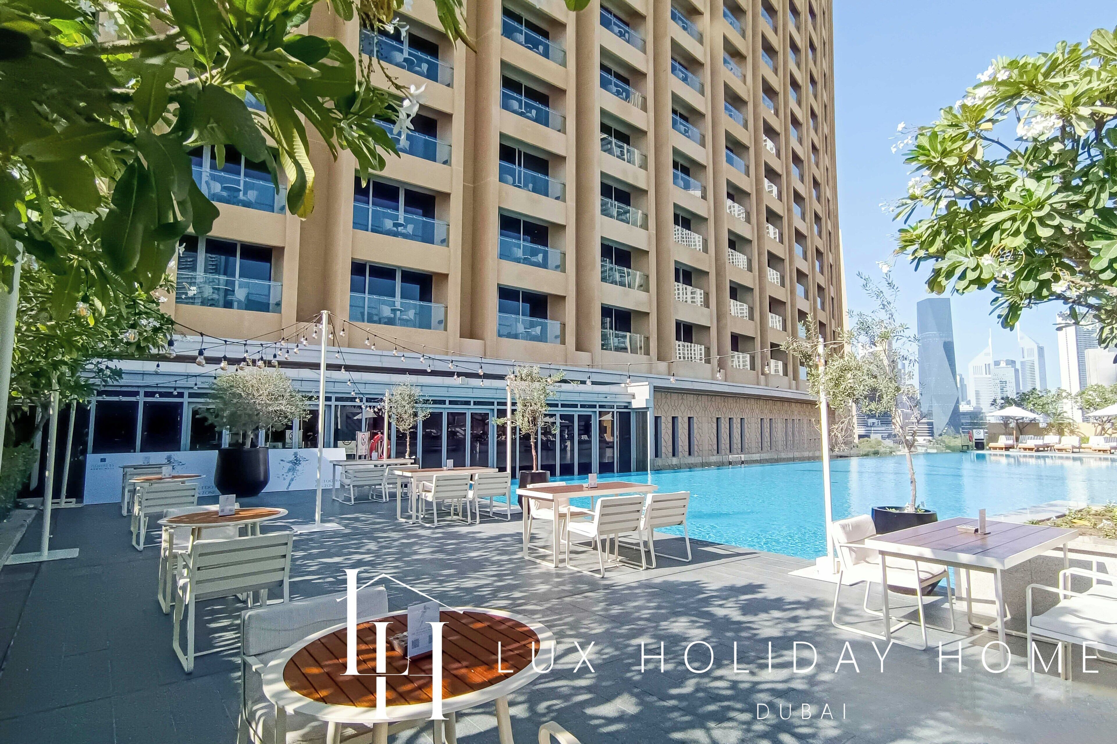 A poolside area with outdoor seating and a view of a tall building.