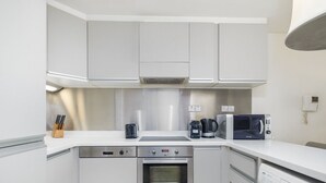 A modern kitchen with white cabinets, a microwave, a coffee maker, and a dishwasher.