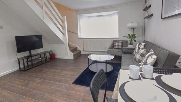 Una sala de estar moderna con televisor, sofá y escalera.