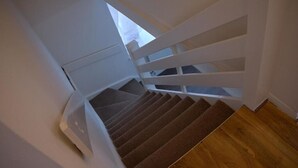 Una escalera con detalles de madera y un rellano alfombrado.