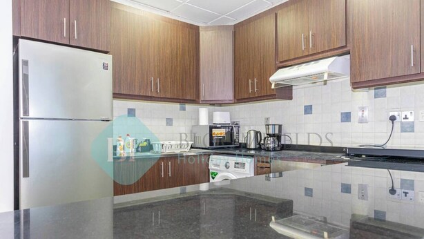 A kitchen with wooden cabinets, a stainless steel refrigerator, a coffee maker, and a dishwasher.