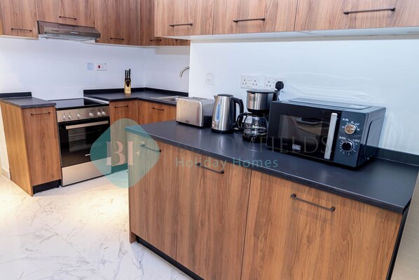 Una cucina moderna con mobili in legno, forno integrato, macchina del caffè e microonde.