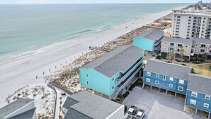Un hôtel situé sur la côte, composé de plusieurs bâtiments à étages, offrant une vue sur la plage et disposant d’un parking.