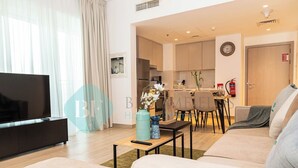Un salon moderne doté d’un téléviseur à écran plat, d’un canapé, d’une table basse et d’un coin repas avec une table et des chaises.