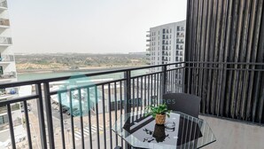 Un balcon avec une table en verre, une chaise et un pot de fleurs.