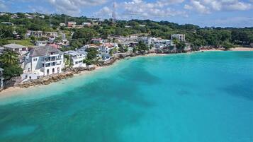 A coastal area with a beach, houses, and a clear blue sea.