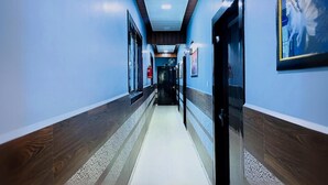 A long, narrow hallway with wooden paneling on the walls and a tiled floor. - Hotel Pragati Heights (Mathura)