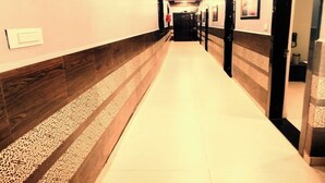 A hallway with a wooden floor and walls, leading to a door at the end. - Hotel Pragati Heights (Mathura)