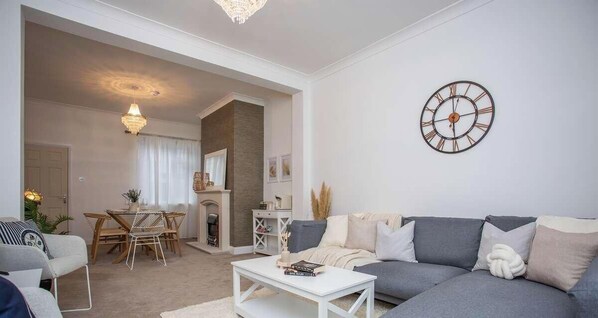 A living room with a sofa, coffee table, and a dining area with chairs and a table.