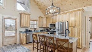 Una cocina amplia con armarios de madera, encimera de granito y una isla central con taburetes de bar.
