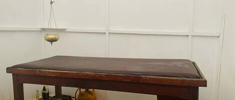 Une table en bois, dont le plateau est d’un brun foncé, est placée contre un mur blanc.