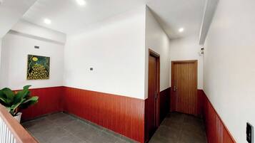 Un couloir avec un lambris rouge et blanc, un sol carrelé et une porte en bois au fond.