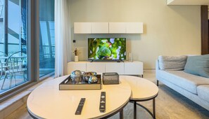 Ein modernes Wohnzimmer mit einem großen Flachbildfernseher, einer Couch, einem Couchtisch und einem Essbereich mit Stühlen und einer Tablett mit Gegenständen.