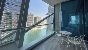 Ein Balkon mit Blick auf einen Fluss und Gebäude, ausgestattet mit weißen Stühlen und einem Tisch.