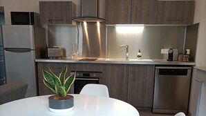 Una cocina moderna con una mesa redonda, sillas blancas y una planta en maceta.