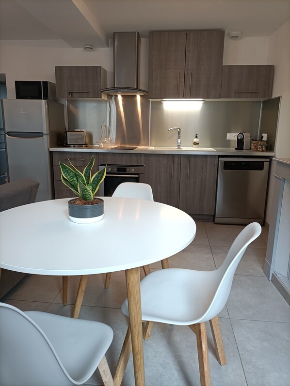 Une cuisine moderne avec une table de salle à manger ronde, des chaises blanches et une plante en pot.