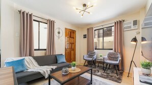 Una sala de estar moderna con un sofá, dos sillones, una mesa de centro y un televisor.