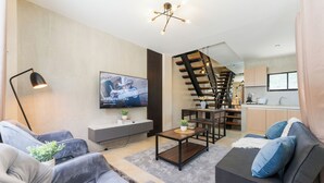 Una sala de estar moderna con un sofá, una mesa de centro y un televisor montado en la pared.