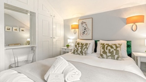 A hotel room with a bed, a desk, a mirror, and two wall-mounted lamps. - Mills Cottage - Sleeps 4 (Henley-On-Thames)