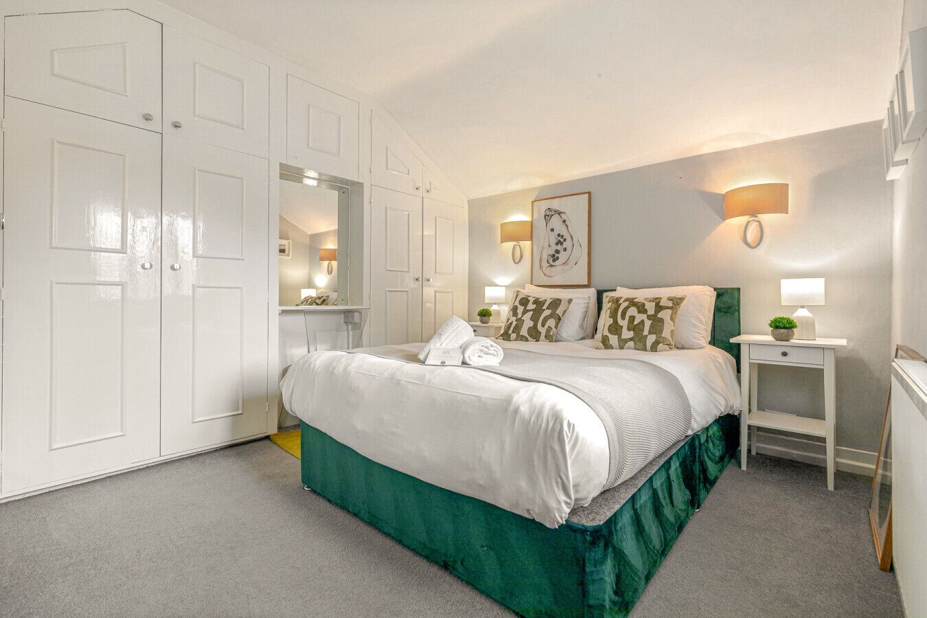 A bedroom with a bed, a nightstand, a mirror, and a wardrobe.