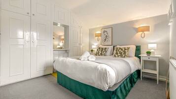 A bedroom with a bed, a nightstand, a mirror, and a wardrobe.
