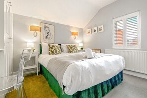 Un dormitorio con una cama, una silla, un ventanal con persianas y lámparas fijadas a la pared.